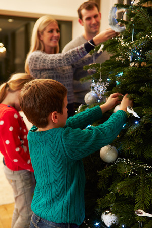Family Decorating Christmas Tree At Home Togetherの写真素材