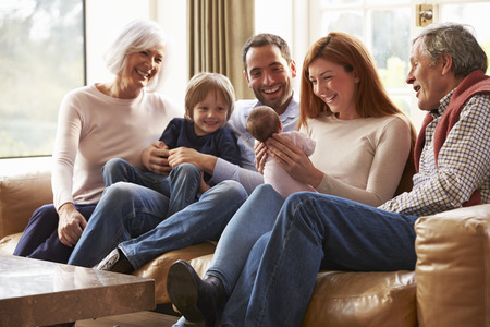 Multi Generation Family Sitting On Sofa With Newborn Babyの写真素材