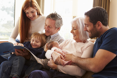Multi Generation Family Sitting On Sofa With Newborn Babyの写真素材