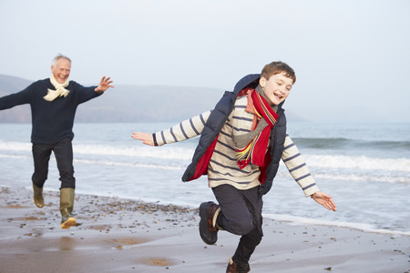 Grandfather And Grandson Running On Winter Beachの写真素材