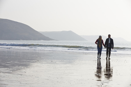 Senior Couple Walking Along Winter Beachの写真素材