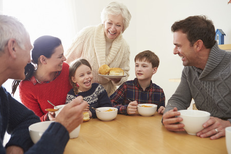 Multi Generation Family Eating Lunch At Kitchen Table