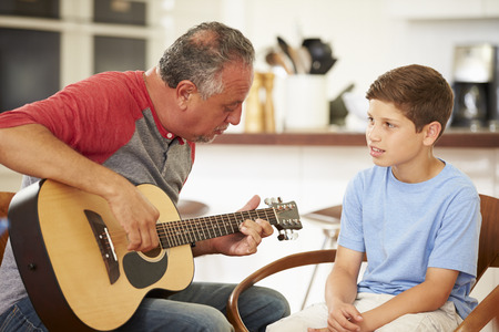 Grandfather Teaching Grandson To Play Guitarの写真素材