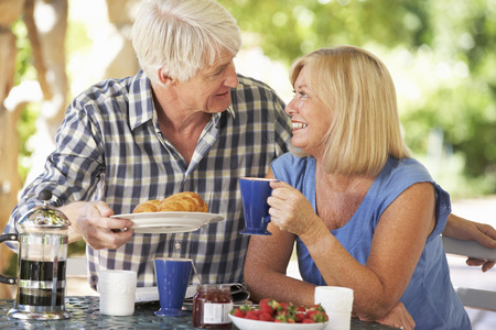 Senior couple eating breakfast outdoorsの写真素材