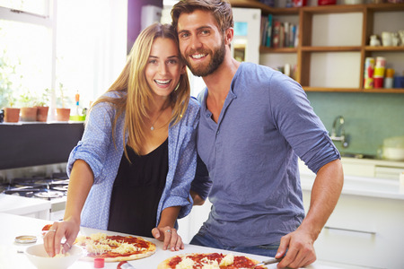 Young Couple Making Pizza In Kitchen Togetherの写真素材