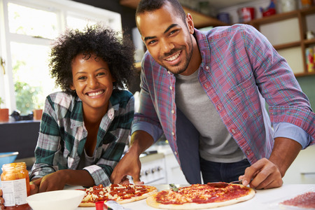 Young Couple Making Pizza In Kitchen Togetherの写真素材