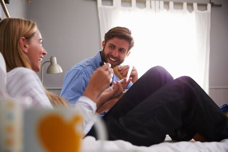 Woman Puts On Make Up As Man Eats Toast In Bedroomの写真素材