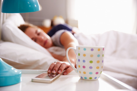 Sleeping Couple Being Woken By Mobile Phone In Bedroomの写真素材