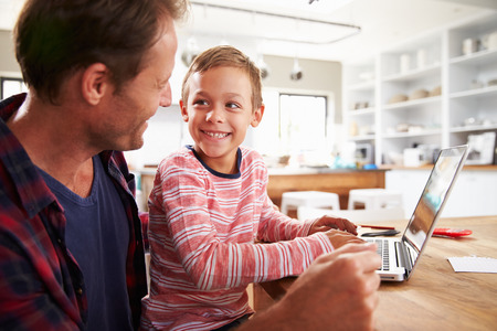 Father and son using laptop computer at home