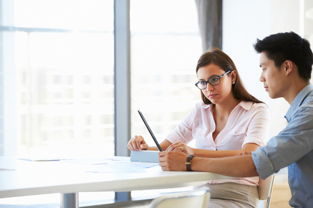 Two people working with digital tablet in empty meeting roomの写真素材