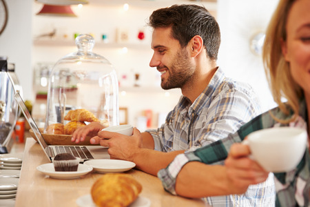 Young man with laptop in a cafeの写真素材