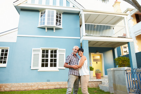 Portrait Of Mature Couple Standing Outside Beautiful Houseの写真素材