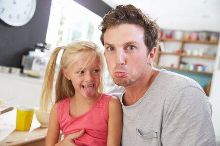 Father And Daughter Making Funny Faces At Breakfast Tableの写真素材