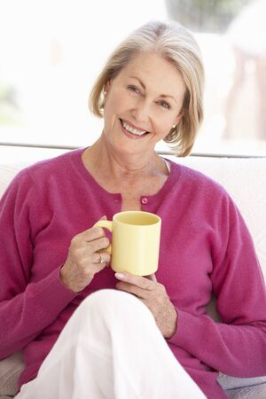 Senior Woman Relaxing At Home With Hot Drinkの写真素材