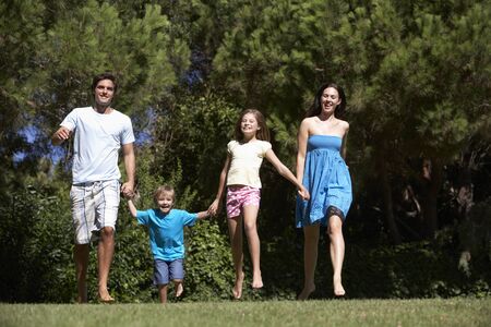 Young Family Running Through Summer Fieldの写真素材