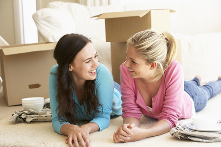 Two Young Women Moving Into New Home Unpacking Boxes