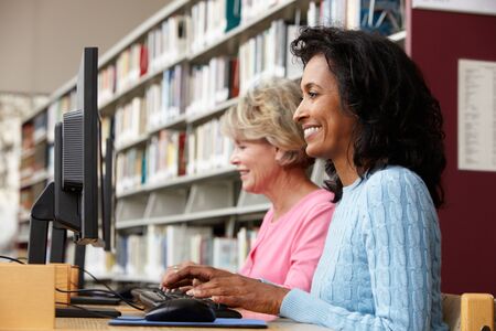 Women working on computers in libraryの写真素材