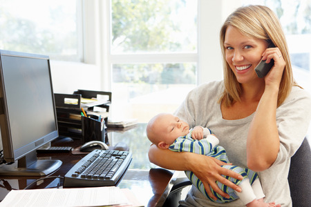 Mother working in home office with babyの写真素材
