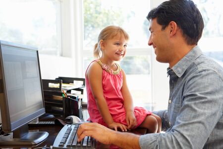 Father working in home office with daughterの写真素材