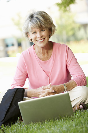 Senior woman using laptop outdoorsの写真素材