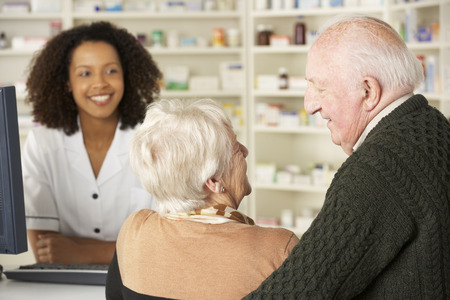 Senior couple in pharmacy with pharmacistの写真素材
