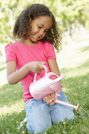 Young African American Girl With Watering Can In Parkの写真素材