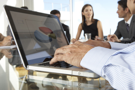 Close Up Of Businessman Using Laptop During Board Meeting Around Glass Tableの写真素材