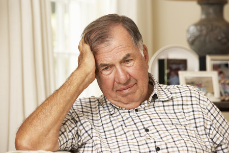 Unhappy Retired Senior Man Sitting On Sofa At Homeの写真素材