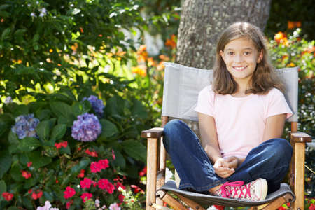 Young Girl Sitting Outdoors In Garden Chairの写真素材
