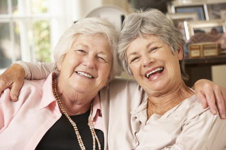 Portrait Of Two Retired Senior Female Friends Sitting On Sofaの写真素材