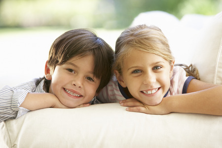 Two Children Relaxing On Sofa At Homeの写真素材