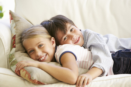 Two Children Relaxing On Sofa At Homeの写真素材