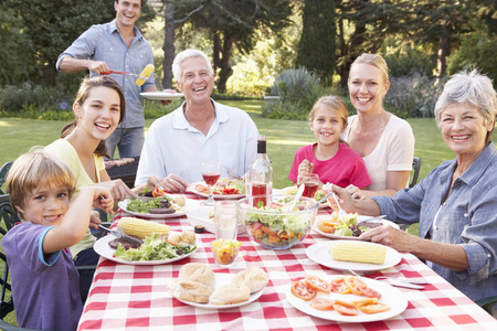 Three Generation Family Enjoying Barbeque In Garden Togetherの写真素材