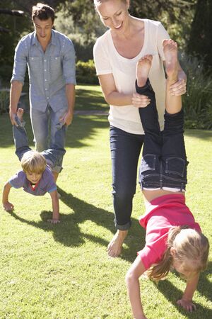 Family Having Wheelbarrow Race In Garden Togetherの写真素材
