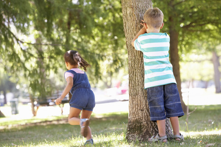 Two Children Playing Hide And Seek In Parkの写真素材