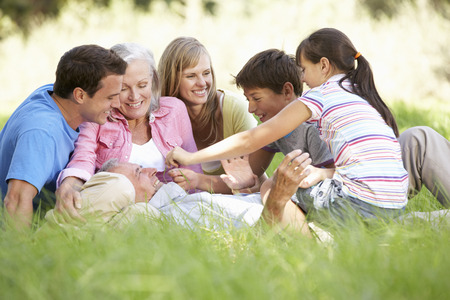 Three Generation Family Relaxing In Summer Field