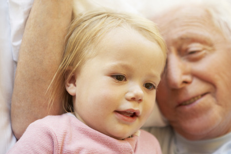Grandfather Cuddling Granddaughter In Bedの写真素材