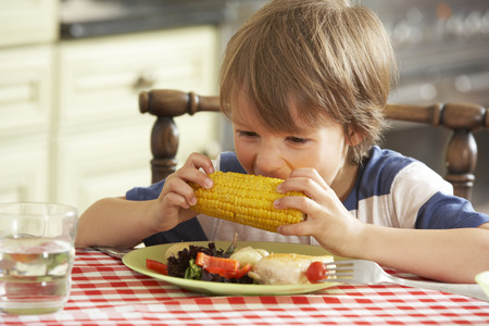 Young Boy Eating Meal In Kitchenの写真素材