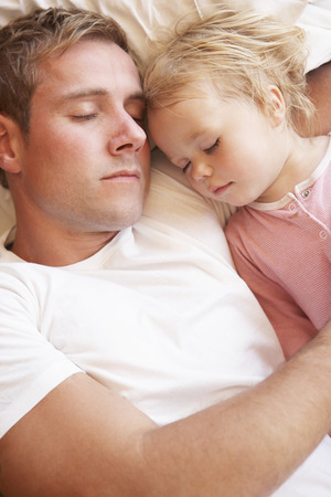 Father And Daughter Sleeping In Bedの写真素材