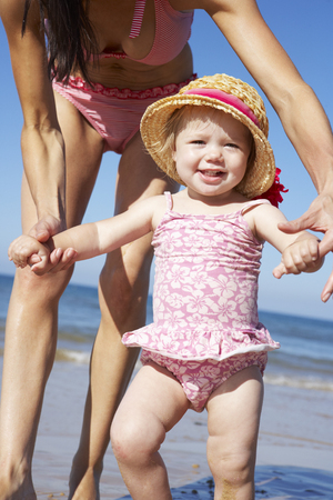 Mother With Young Daughter Walking Along Beach Togetherの写真素材
