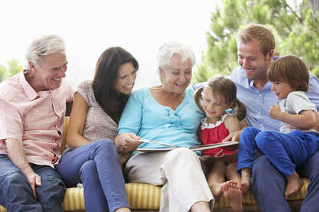 Multi Generation Family Reading Book On Garden Seatの写真素材