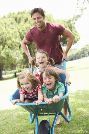 Father Giving Children Ride In Wheelbarrowの写真素材