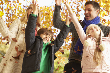 Family Throwing Leaves In Autumn Garden