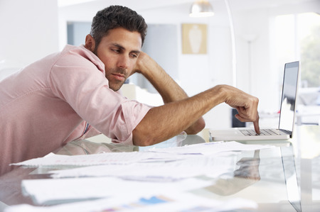 Stressed Man Working At Laptop In Home Officeの写真素材