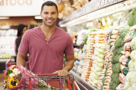 Man Pushing Trolley By Produce Counter In Supermarketの写真素材