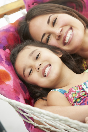 Mother And Daughter Relaxing In Garden Hammock Togetherの写真素材