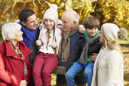 Multl Generation Family By Wooden Fence On Autumn Walk