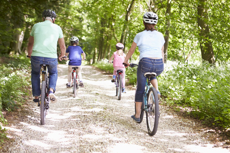 Grandparents With Grandchildren Cycling In Countryside