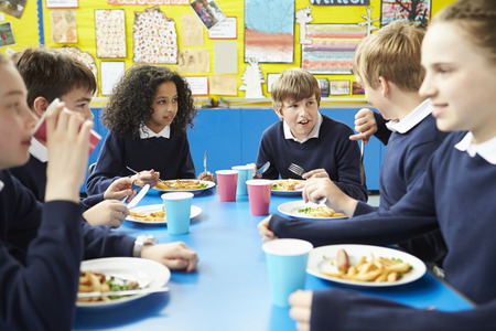 Schoolchildren Sitting At Table Eating Cooked Lunch