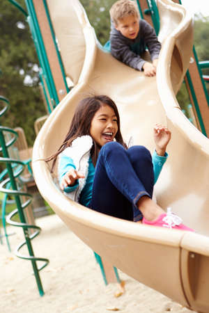 Young Girl Playing On Slide In Playgroundの写真素材